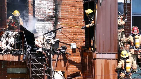 Fireman working with a burn wood piece to remove debris Stock Footage 90337522
