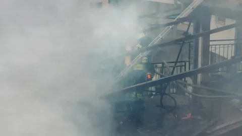Firemen in action on burning ruins of building Stock Footage 237210848