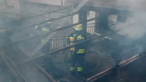 Firemen in action on burning ruins of building Stock Footage 237210905