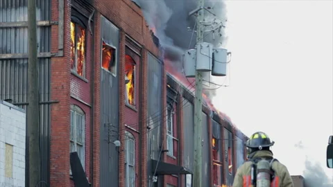 Firemen in action at large building fire. Flames shooting out of building with b Stock Footage