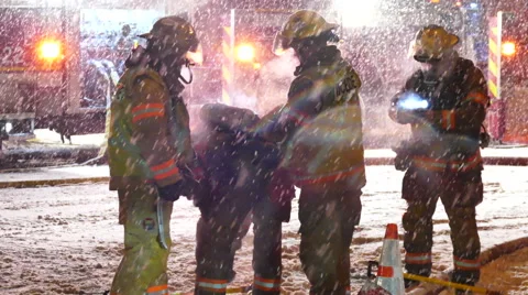 Firemen adjusting equipment at scene of fire with heavy snow fall - Commercial Video stock 49696348