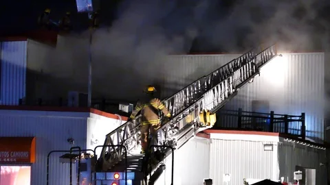 FIremen on the bottom of a ladder fighting smoke Stock-Footage 104233380