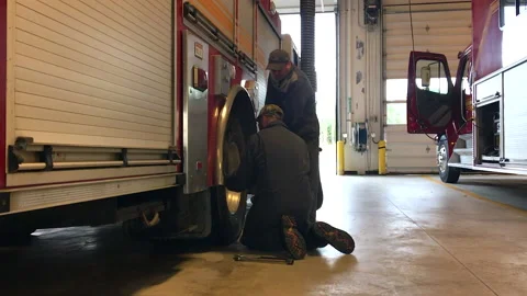 Firemen checking the bolts on the firetuck Stock Footage 208078890