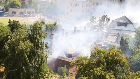 Firemen continue to extinguish a strongly smoking roof of an old house Stock-Footage 79506200