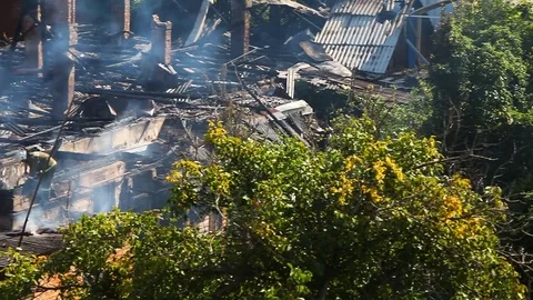 Firemen continue to extinguish a strongly smoking roof of an old house Stock Footage 80020528