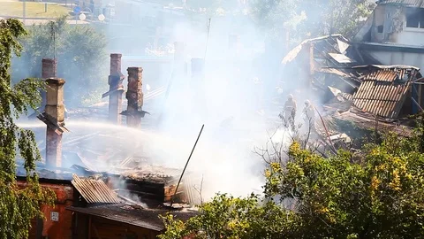 Firemen continue to extinguish a strongly smoking roof of an old house Stock Footage 80021223