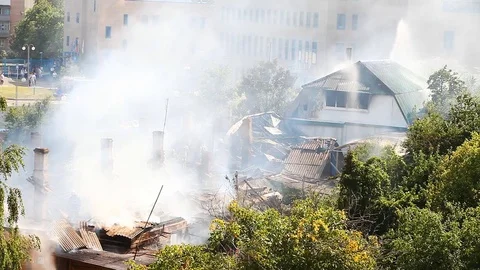 Firemen continue to extinguish a strongly smoking roof of an old house Stock Footage 80258706