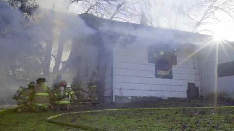 Firemen crouch on their knees by a burning house Stock Footage 60752391