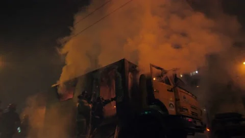 Firemen extinguish a large burning car in the middle of the road Stockbeeldmateriaal 155660242