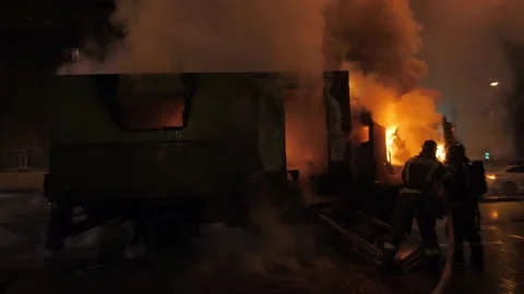 Firemen extinguish a large burning car in the middle of the road Stockbeeldmateriaal 155660291