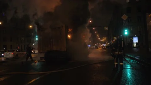 Firemen extinguish a large burning car in the middle of the road Video stock 155660792
