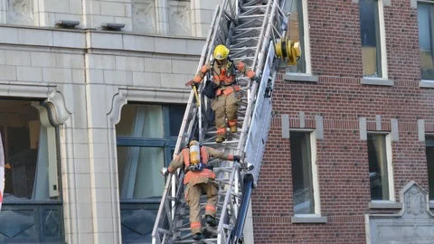 Firemen guetting off a ladder Stock Footage 90360170