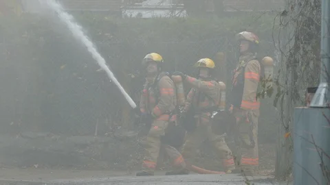 Firemen with hoses with smoke Stock Footage 120120196