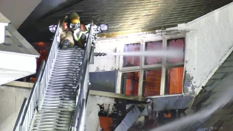 Firemen laying down on ladder watering structure fire Video stock 139657525