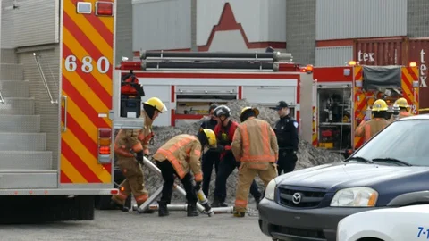 Firemen picking up hydraulic ram piston extrication tools on the ground Stock Footage 128098965