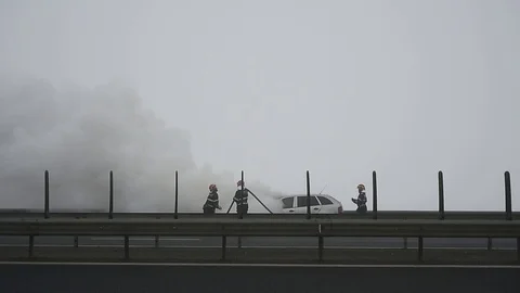 Firemen try to extinguish a burning car on a highway Video stock 101550545