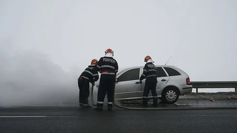Firemen try to extinguish a burning car on a highway Video stock 101550568