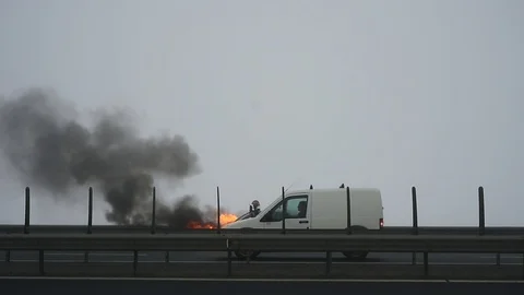 Firemen try to extinguish a burning car on a highway Video stock 101550630