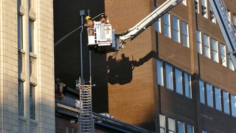Firemen watering building while the ladder is moving Stock Footage 90360100