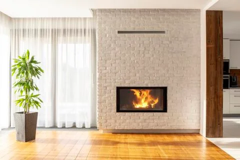 Fireplace on brick wall in bright living room interior of house with plant an Stock Photos