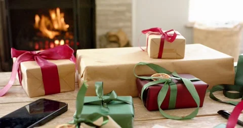 Fireplace igniting logs, casting flickering flames across wrapped gift boxes on Stock Footage 336437155