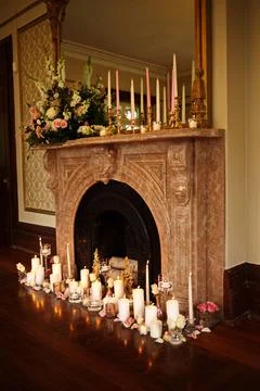 A fireplace mantle covered in candles with flowers on top of it Stock Photos