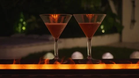 Fireside two glasses of alcohol on bar with fire glow adding touch of warmth and Stock Footage 312507871