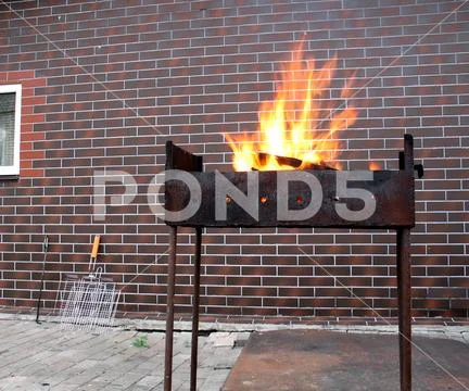 Firewood and fire in the old rusty charcoal grill Stock Photos