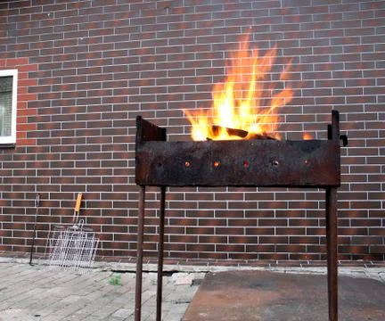 Firewood and fire in the old rusty charcoal grill Stock Photos