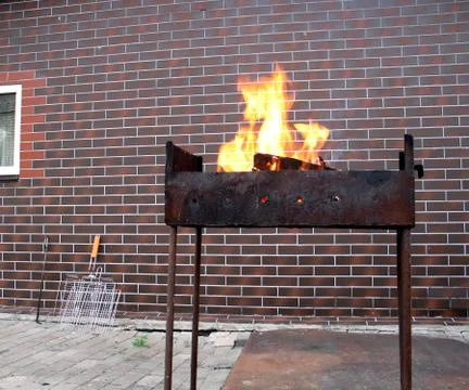 Firewood and fire in the old rusty charcoal grill Stock Photos