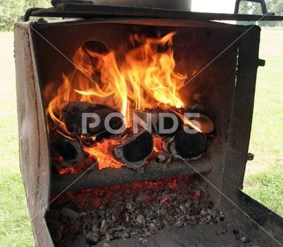 Firewood and fire in the old rusty grill Stock Photos