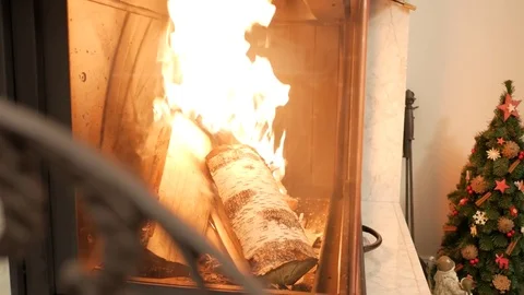 Firewood blazes bright behind a fireproof glass of the fireplace. Handheld shot Stock Footage 72633387