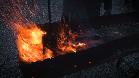 Firewood in the grill. A man breaks down already burned wood to make coals Video stock 101194175