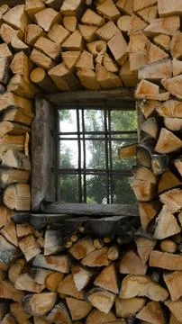 Firewood stack of logs framing a house window Stock Photos