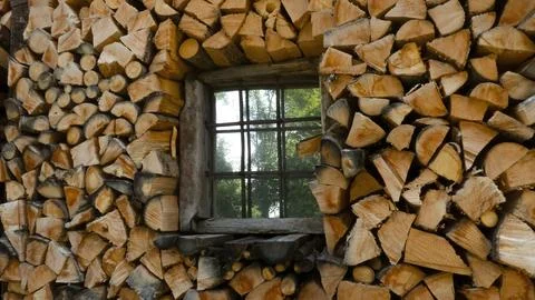 Firewood stack of logs framing a house window Stock Photos