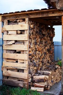 Firewood stacked in rows under a canopy Stock Photos