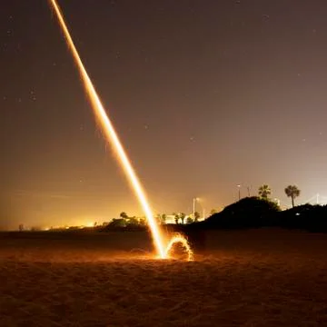 A firework exploding on a beach at night Stock Photos
