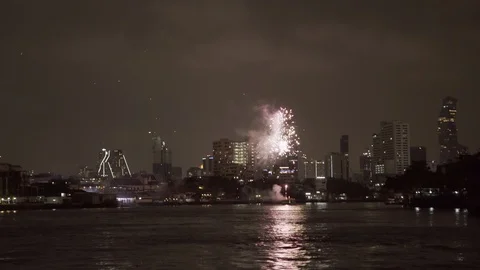 Firework exploding over buildings with smoke in city by river against sky at Stock Footage 129260384