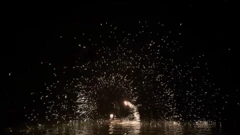 Firework explosion over calm sea at night with reflections and glowing sparks Stock Footage 316112292