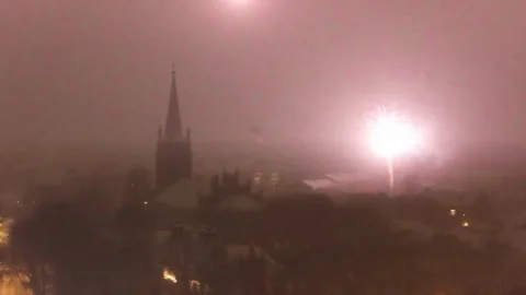 Fireworks burst in red sky over Riga church during snowy winter celebration Stock Footage 326294520