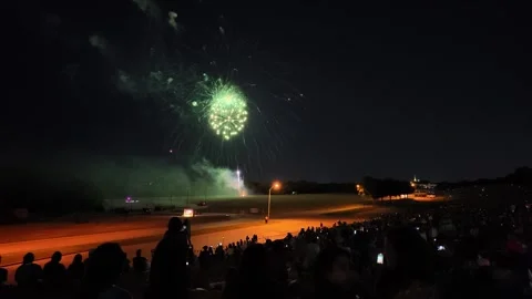 Fireworks display over a field with a crowd watching at night Stock Footage 340942019