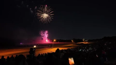 Fireworks display over a field with a large crowd watching at night Stock-Footage 340942072