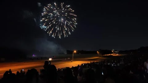 Fireworks display over open field at night with crowd watching Stock Footage 340942062
