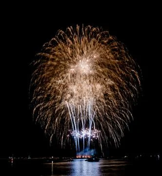 Fireworks explode brightly above the water in this photograph during the night Foto stock