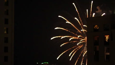 Fireworks explode brightly over the ocean, framed by high-rise buildings Video stock 313339860
