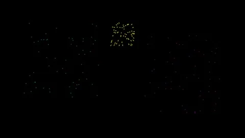 Fireworks explode in brilliant multi-colored bursts across a dark night sky Stock Footage 345947717