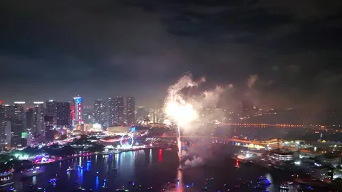 Fireworks explode in dazzling rhythm with glittering city lights and anchored Video stock 313467260