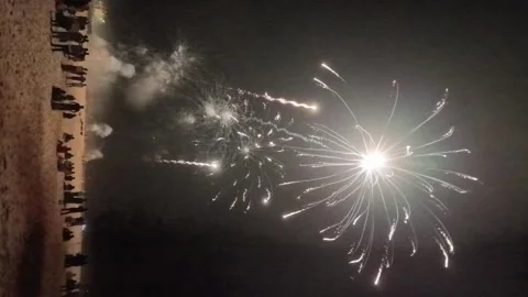 Fireworks explode in the night sky as a crowd gathers at Torreira Beach during t Stock Footage 344806236
