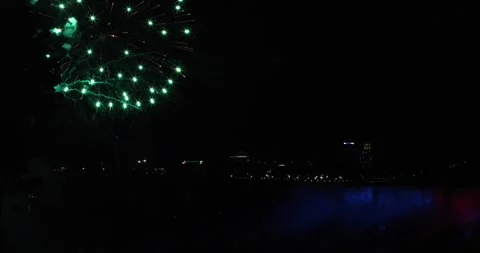 Fireworks explode over Niagara Falls at night, waterfall lit in red and blue Video stock 320025138