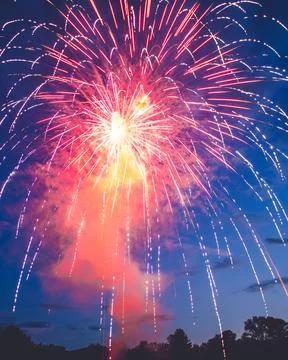 Fireworks explode over the setting sun Stock Photos